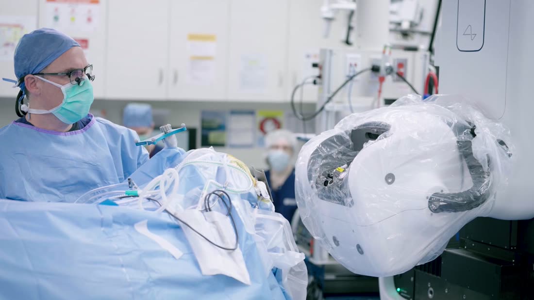 OP-Saal mit Chirurg und dem weißen kuppelförmigen Neuralink-Operationsroboter am OP-Tisch